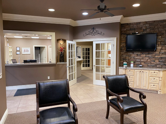 front office of dental clinic with tv, chairs and reception area