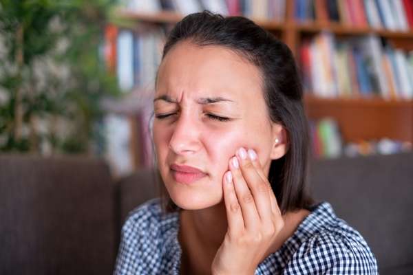 face of a lady in pain with eyes closed and hand on her jaw